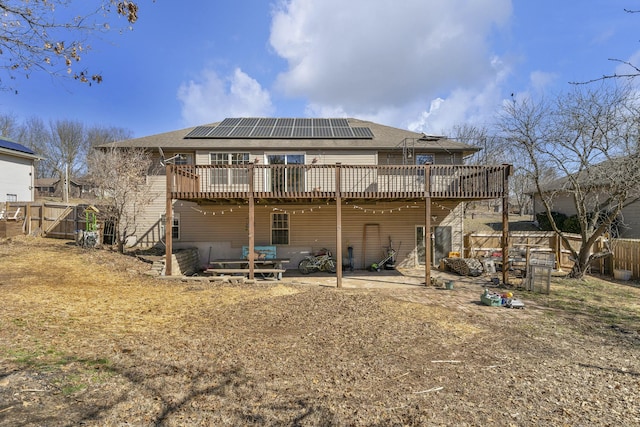 back of property with solar panels, a patio, a gate, fence, and a wooden deck