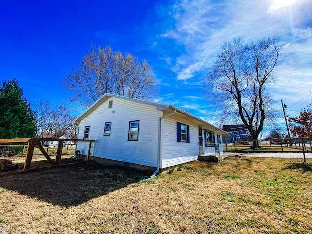 view of side of home with fence and a lawn