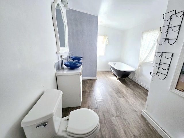 full bathroom featuring a soaking tub, a healthy amount of sunlight, toilet, and wood finished floors