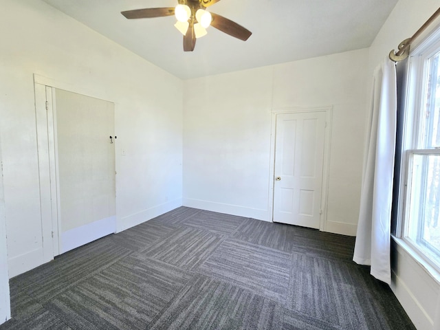 spare room featuring dark carpet and baseboards