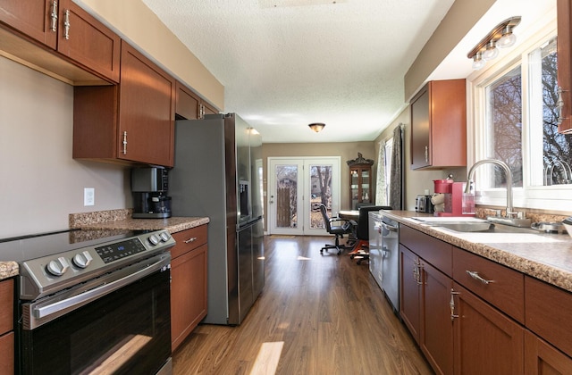 kitchen featuring appliances with stainless steel finishes, dark wood finished floors, a sink, and plenty of natural light