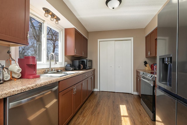 kitchen with a sink, baseboards, light countertops, appliances with stainless steel finishes, and dark wood finished floors