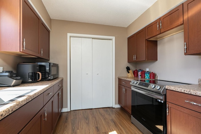 kitchen featuring dark wood finished floors, brown cabinets, stainless steel electric stove, a textured ceiling, and black microwave