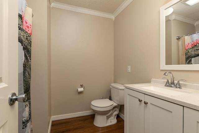 bathroom featuring toilet, ornamental molding, vanity, wood finished floors, and baseboards