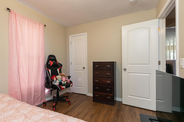bedroom featuring dark wood-style floors, a textured ceiling, and baseboards