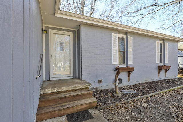 property entrance featuring crawl space and brick siding