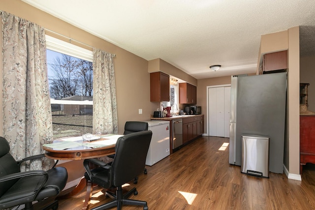 interior space with appliances with stainless steel finishes, dark wood-type flooring, light countertops, a textured ceiling, and a sink