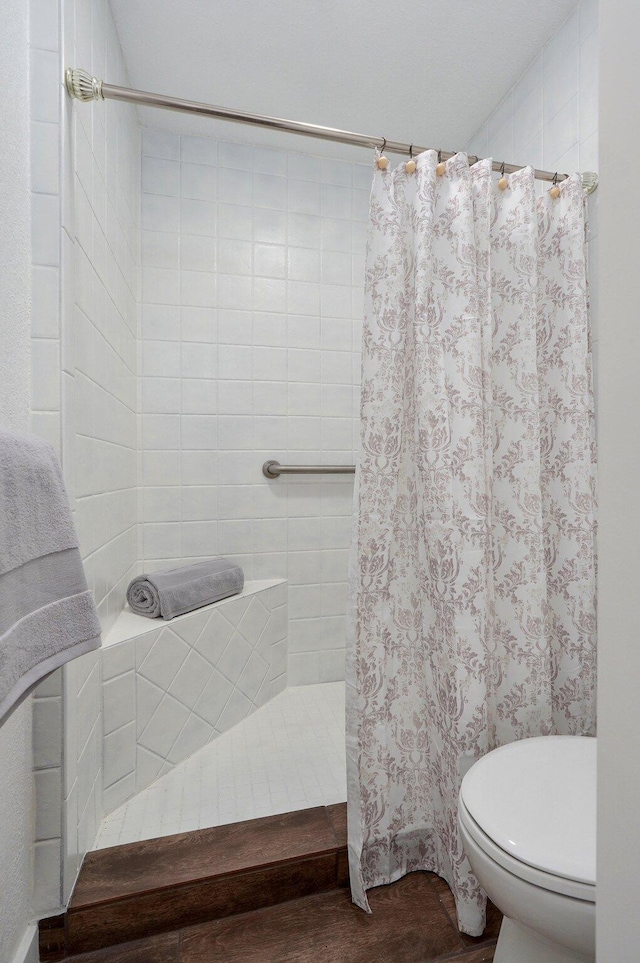 bathroom with a tile shower and toilet