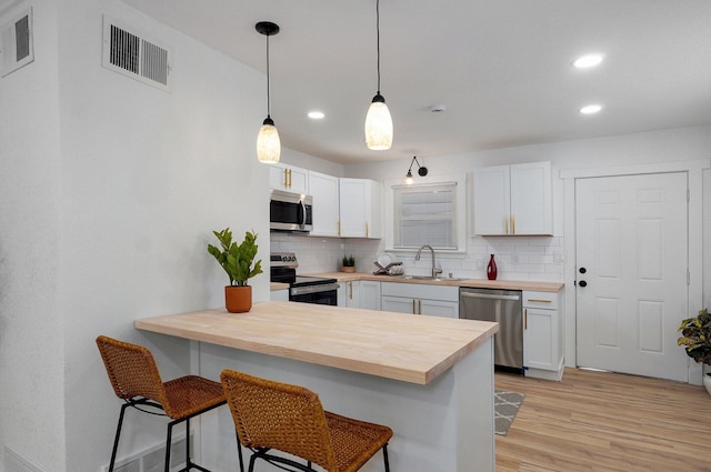 kitchen featuring visible vents, appliances with stainless steel finishes, a kitchen breakfast bar, a sink, and backsplash