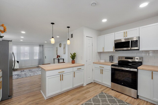 kitchen with light wood-type flooring, tasteful backsplash, appliances with stainless steel finishes, and wooden counters