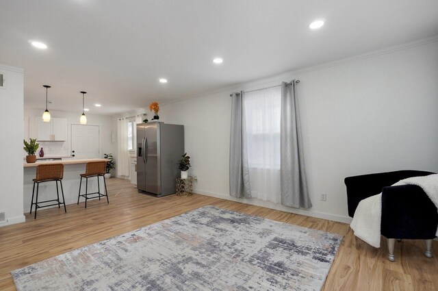 kitchen with decorative backsplash, stainless steel fridge, light wood-style flooring, and a kitchen breakfast bar