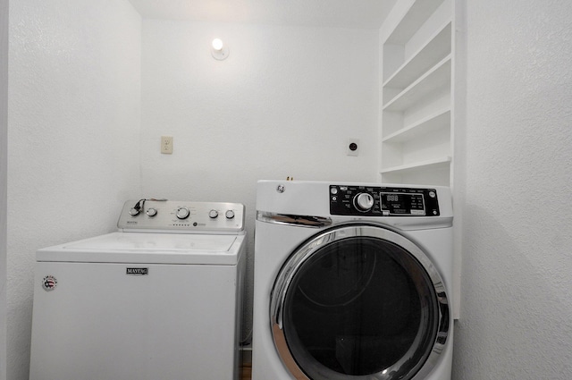 washroom featuring laundry area, a textured wall, and washing machine and clothes dryer