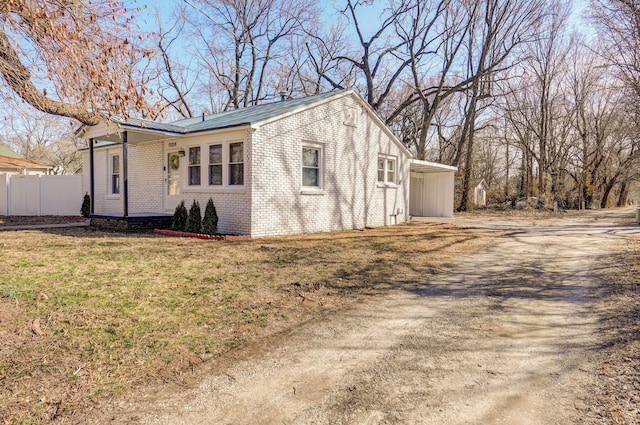 exterior space featuring brick siding, a lawn, and fence