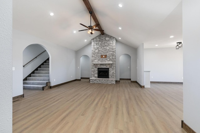 unfurnished living room featuring light wood finished floors, beamed ceiling, a fireplace, and a ceiling fan