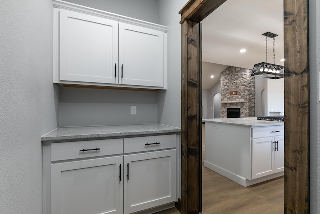 kitchen with recessed lighting, light wood-style floors, open floor plan, white cabinets, and a stone fireplace