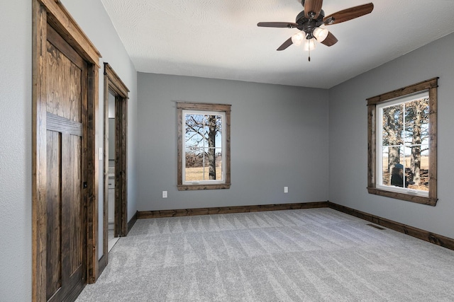 unfurnished bedroom featuring light carpet, baseboards, multiple windows, and visible vents