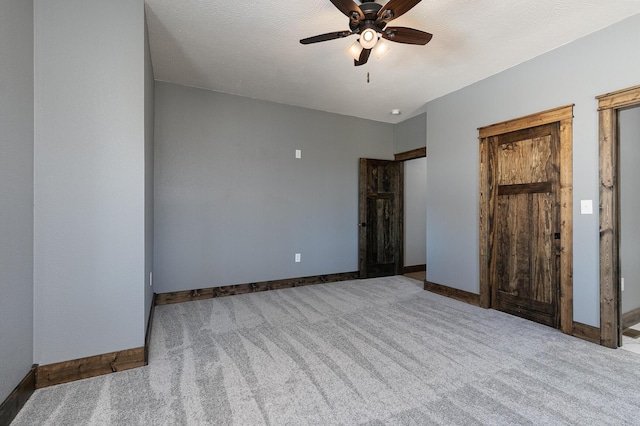 unfurnished bedroom with carpet floors, ceiling fan, a textured ceiling, and baseboards