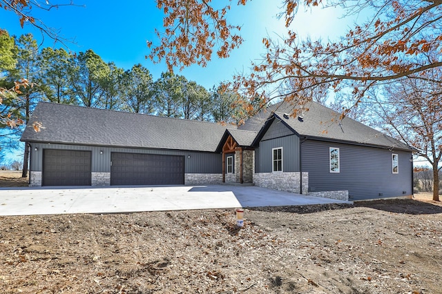 view of front of home with an attached garage, stone siding, and roof with shingles