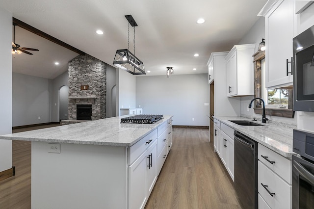 kitchen with gas cooktop, a sink, white cabinets, black dishwasher, and a center island