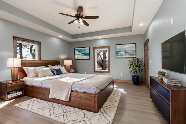 bedroom featuring baseboards, light wood-style flooring, ceiling fan, a tray ceiling, and recessed lighting