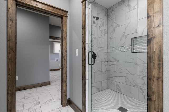 bathroom with marble finish floor, a stall shower, and baseboards