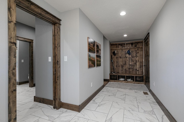 hall featuring marble finish floor, baseboards, a textured ceiling, and recessed lighting