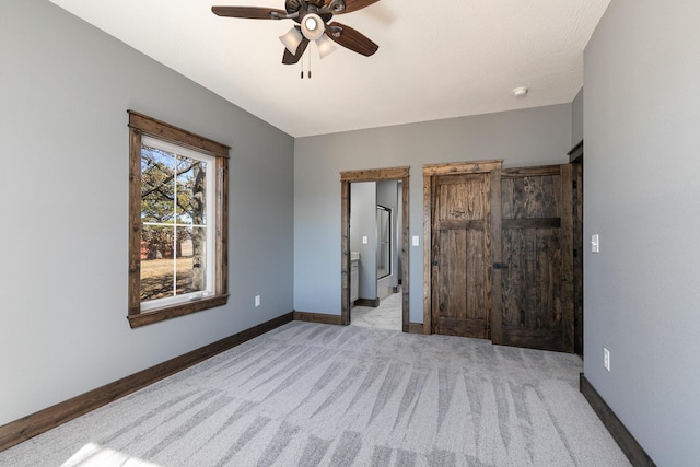 bedroom featuring a ceiling fan, light carpet, baseboards, and ensuite bathroom