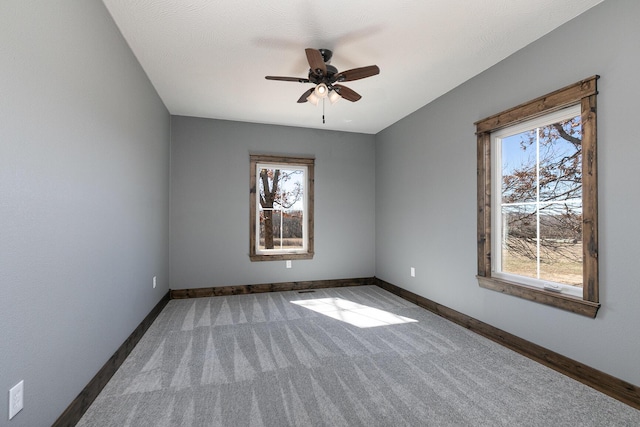 empty room with ceiling fan, carpet, and baseboards