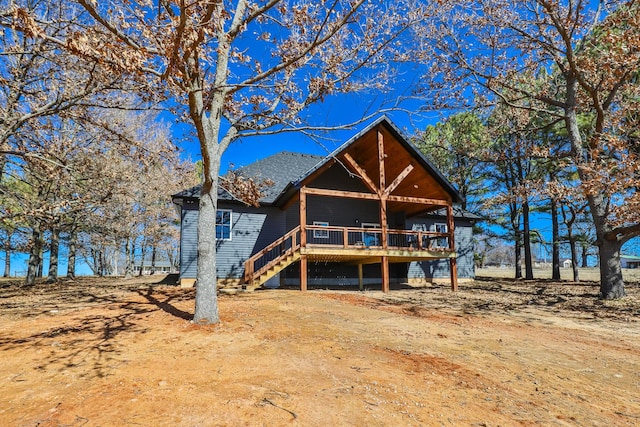 view of front facade with a shingled roof, stairway, and a wooden deck