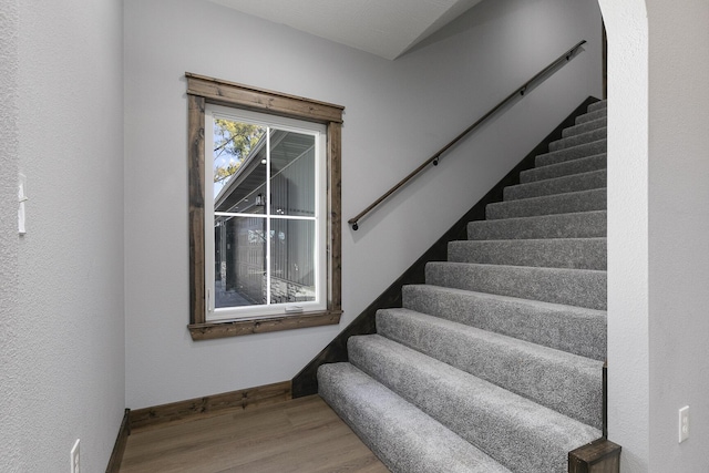 staircase featuring baseboards and wood finished floors