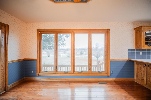 unfurnished dining area with wainscoting, visible vents, and wallpapered walls