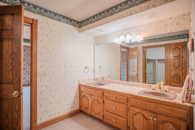 bathroom featuring baseboards, a sink, and wallpapered walls