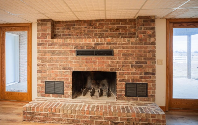 details with a brick fireplace, visible vents, and wood finished floors