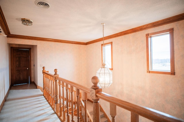 hall with baseboards, visible vents, crown molding, and an upstairs landing