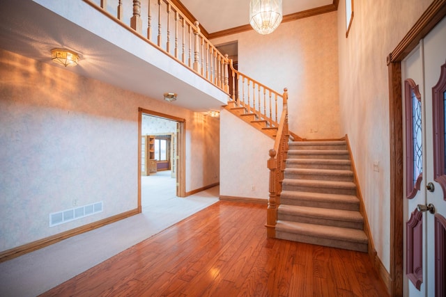 foyer featuring baseboards, visible vents, wood finished floors, a high ceiling, and stairs