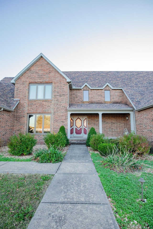 view of front of property with brick siding and roof with shingles