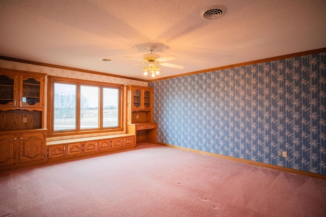 spare room with wallpapered walls, visible vents, ornamental molding, and a textured ceiling