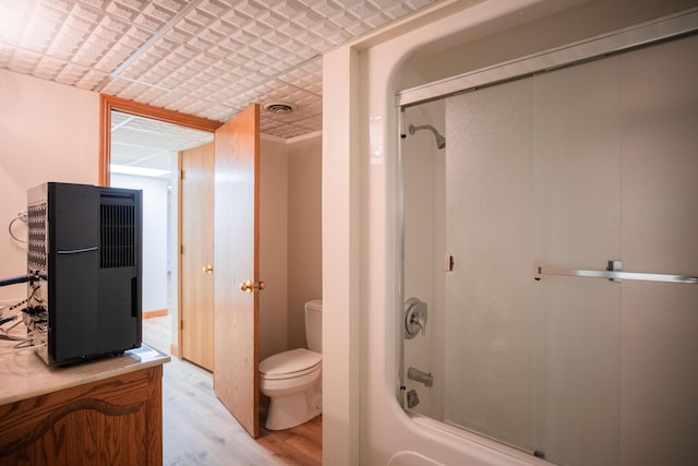 bathroom with toilet, shower / bath combination with glass door, visible vents, and wood finished floors