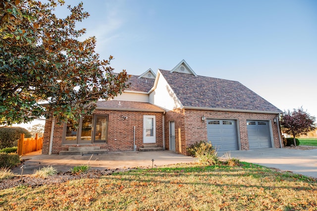 view of front facade featuring brick siding, a shingled roof, entry steps, a front yard, and driveway