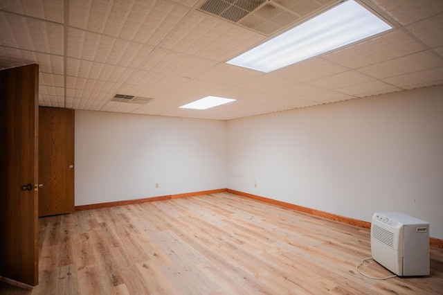 spare room with a drop ceiling, wood finished floors, visible vents, and baseboards