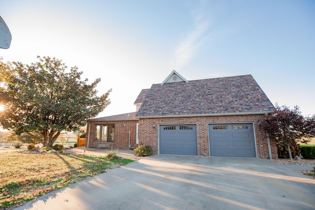 view of front of home with a garage, driveway, roof with shingles, and brick siding