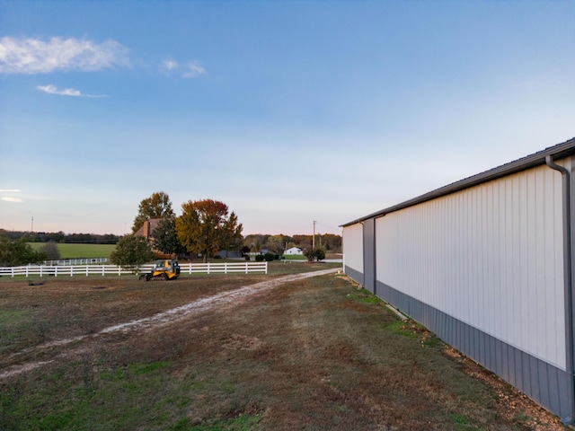 view of yard with a pole building, fence, an outbuilding, and a rural view