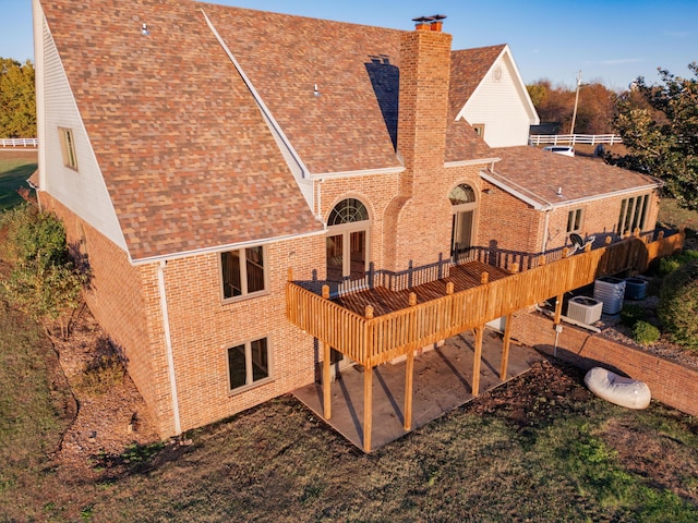 rear view of property featuring roof with shingles, brick siding, and a chimney