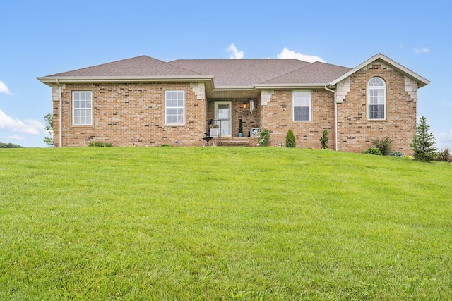 ranch-style home featuring a shingled roof, a front yard, and brick siding