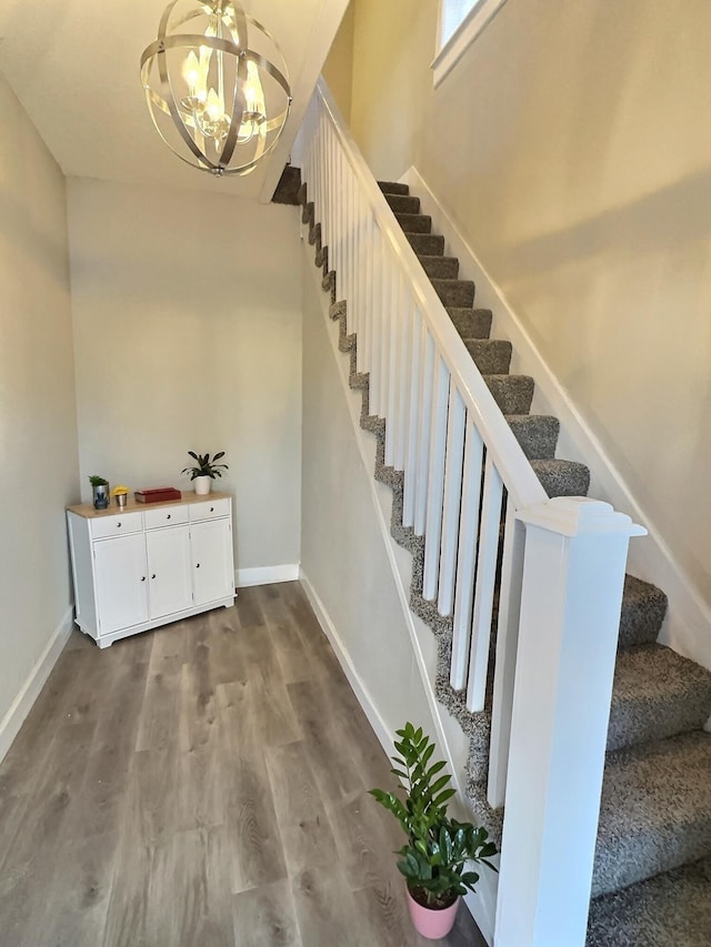 stairs featuring a chandelier, wood finished floors, and baseboards