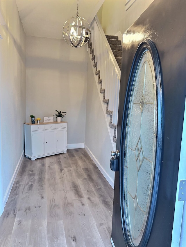 foyer with light wood-type flooring, stairs, baseboards, and a notable chandelier