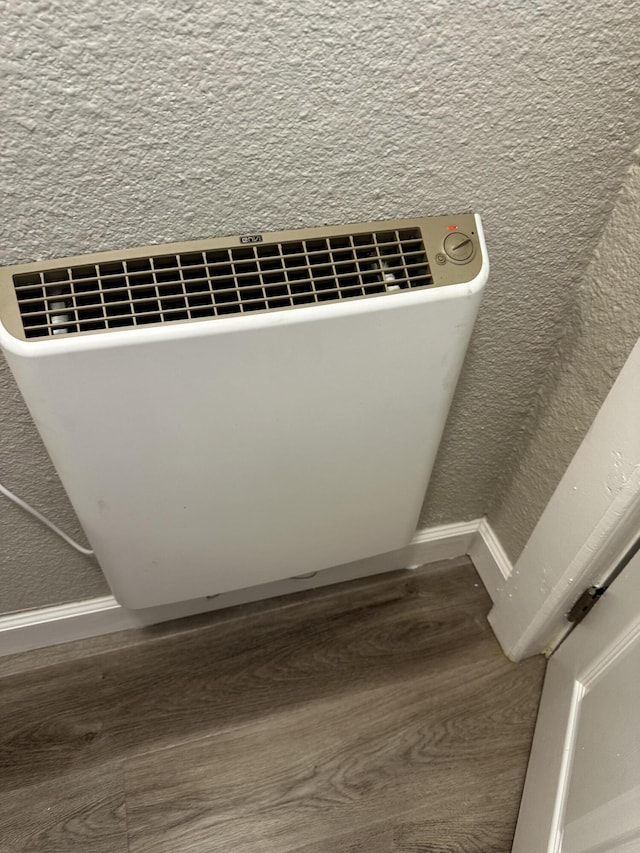 room details featuring a textured wall, radiator heating unit, and wood finished floors