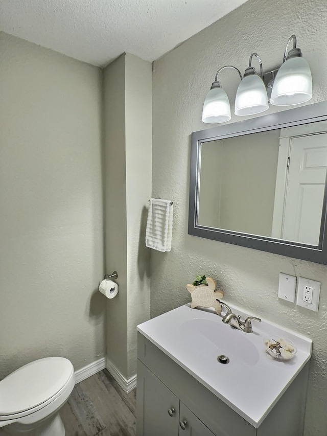 bathroom featuring a textured wall, vanity, a textured ceiling, and wood finished floors