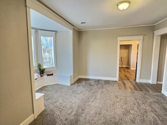 carpeted spare room with crown molding and baseboards