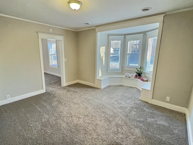 carpeted spare room featuring baseboards, visible vents, and crown molding